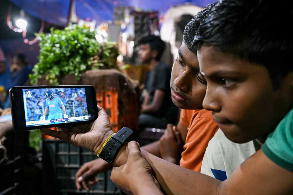 Children watch the India-Pakistan World Cup game on a mobile phone in a vegetable market in Delhi