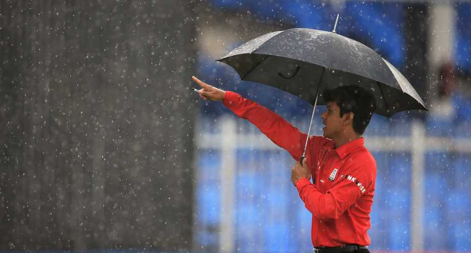 Umpire Sharfuddoula shelters under an umbrella