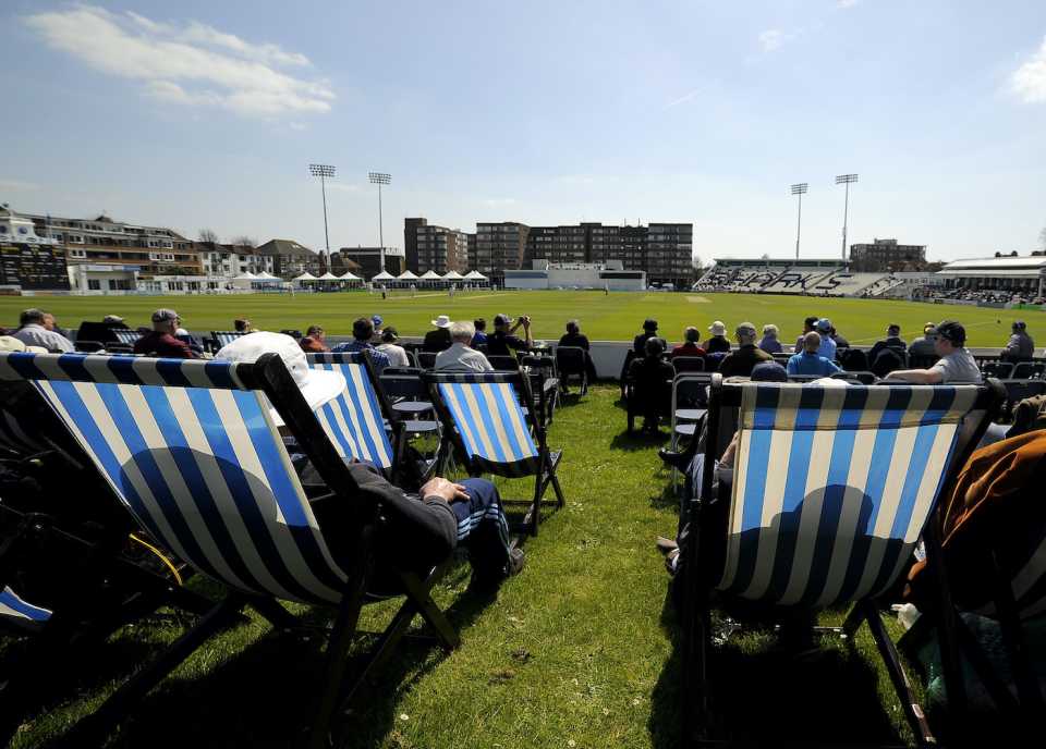 Spectators enjoy the sun and cricket from deck chairs