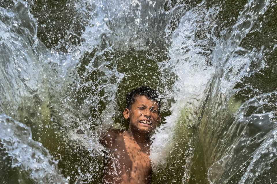 A child takes a dip in a lake to cool off during the heatwave in Dhaka