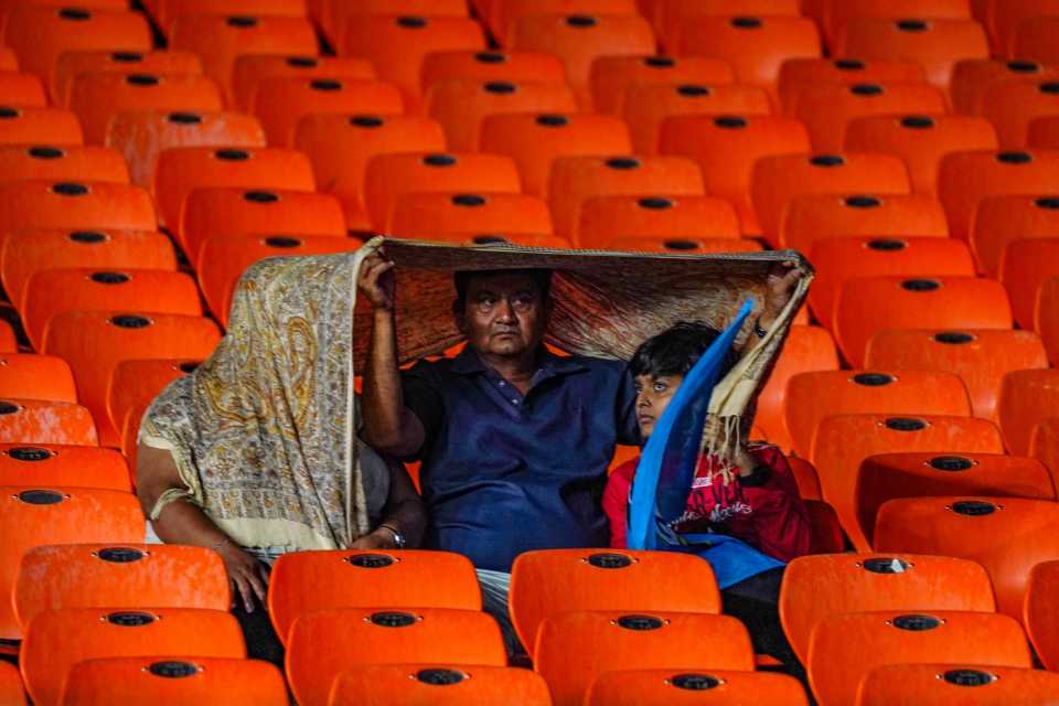 One size fits all: a trio takes shelter from the rain in Ahmedabad, Gujarat Titans vs Kolkata Knight Riders, IPL 2024, Ahmedabad, May 13, 2024