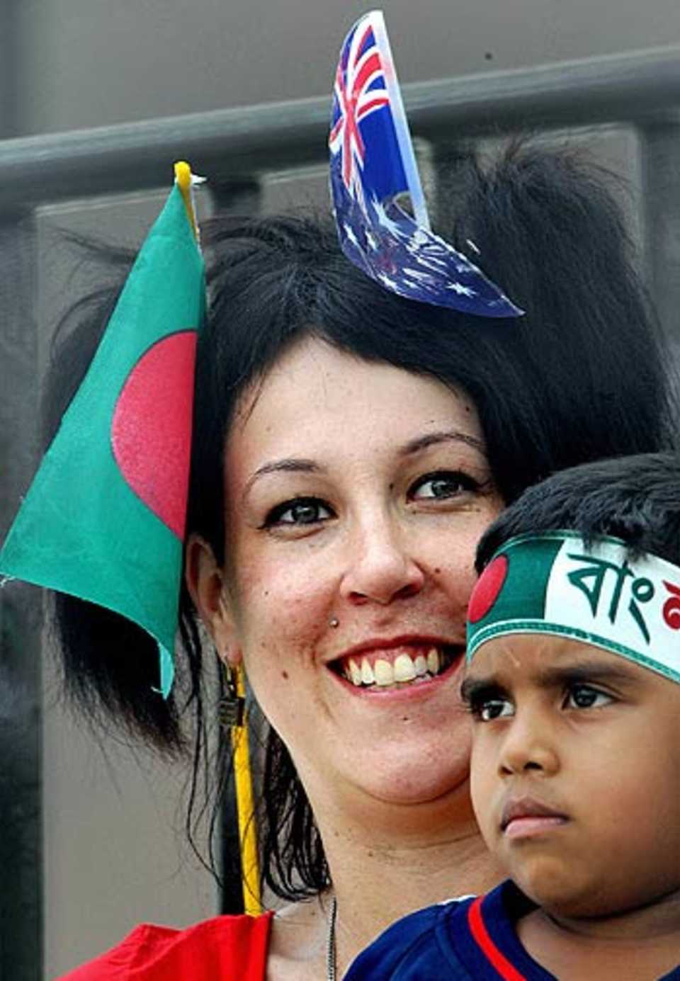 An Australian cricket fan holds a Bangladeshi boy as she wears two minature flags of Bangladesh