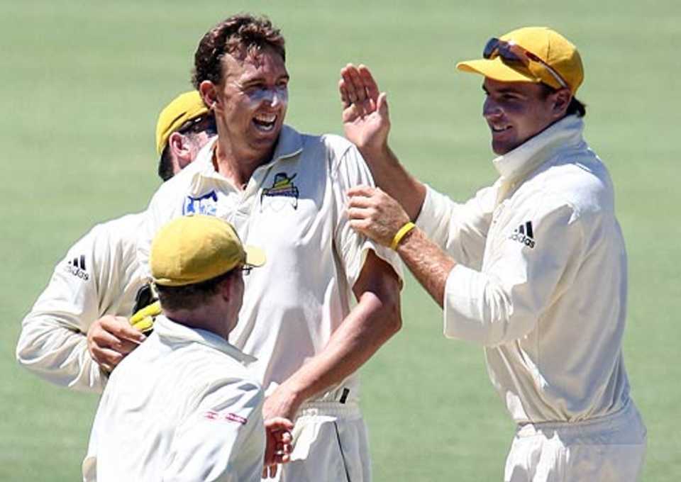 Brett Dorey's team-mates congratulate him on getting a wicket