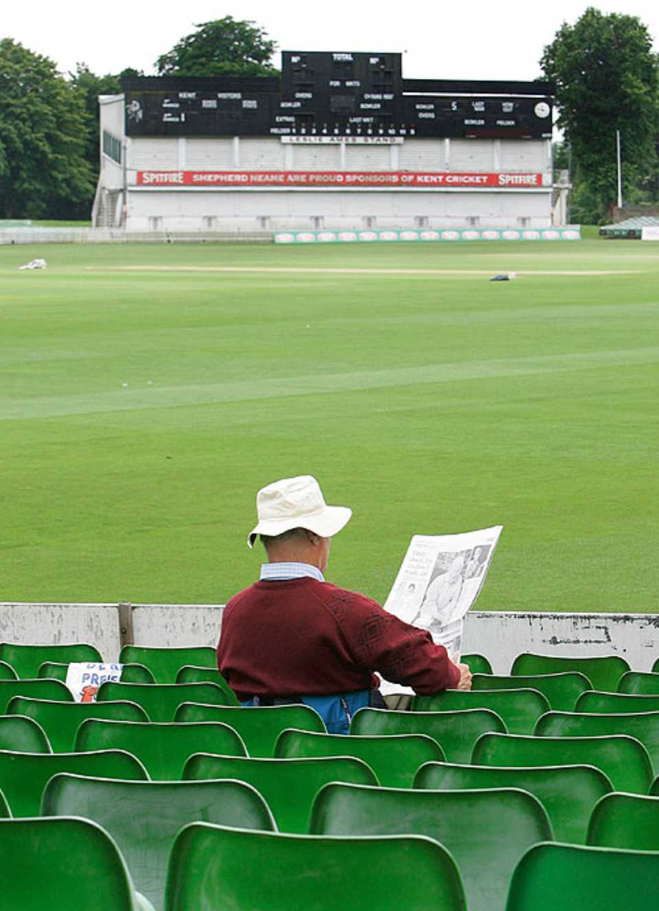 A fan reads the paper after play was called off in Canterbury