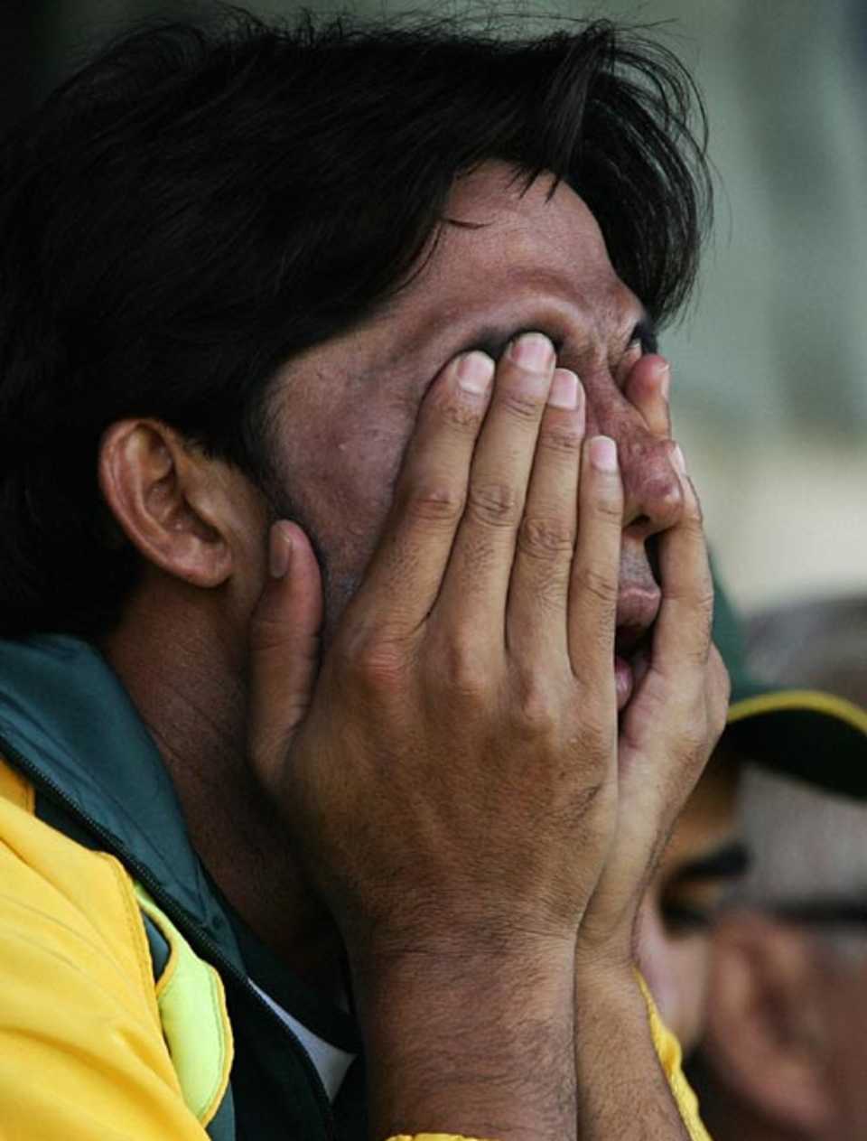 Mohammad Asif rubs his eyes while sitting on the sidelines