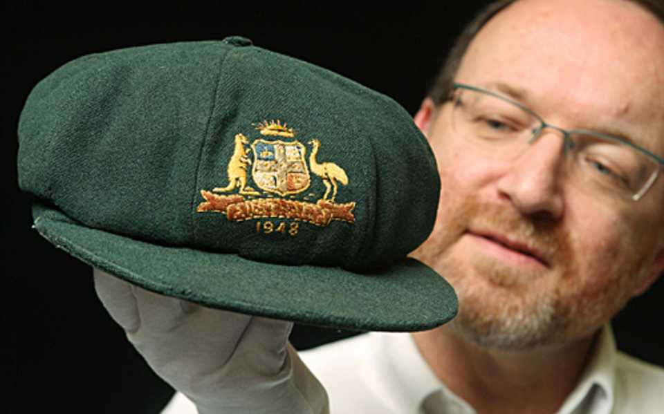 The auctioneer, Charles Leski, inspects the Baggy Green cap worn by Don Bradman during the 1948 'Invincibles' tour