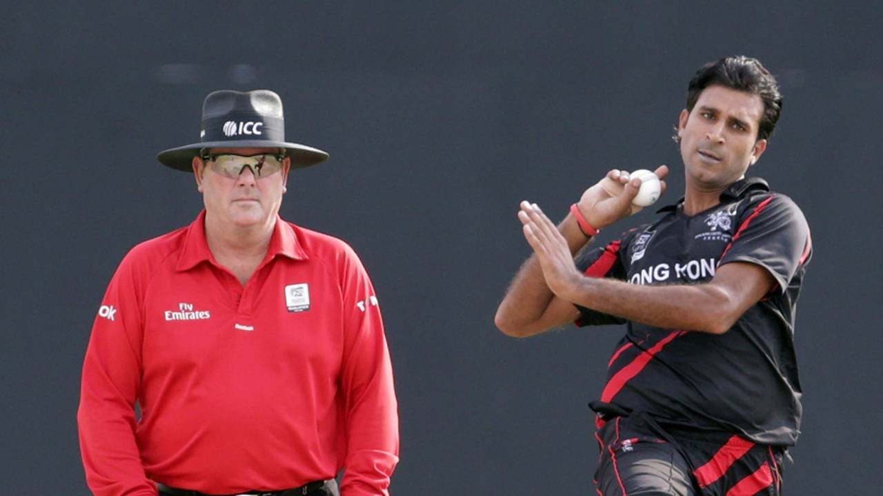 Tanwir Afzal of Hong Kong coming in to bowl along side umpire Derek Walker during ICC World Twenty20 Qualifier between Ireland and Hong Kong at the Zayed Cricket Stadium on November 24, 2013 in Abu Dhabi, United Arab Emirates. (Photo by Graham Crouch-IDI/IDI via Getty Images)
