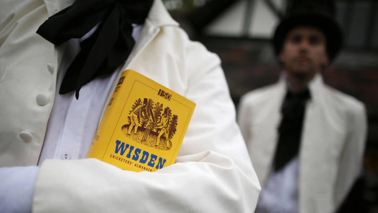 A team member holds a copy of the <i>Wisden Cricketers' Almanack</i> during a Victorian cricket match, Vincent Square, London, May 29, 2013