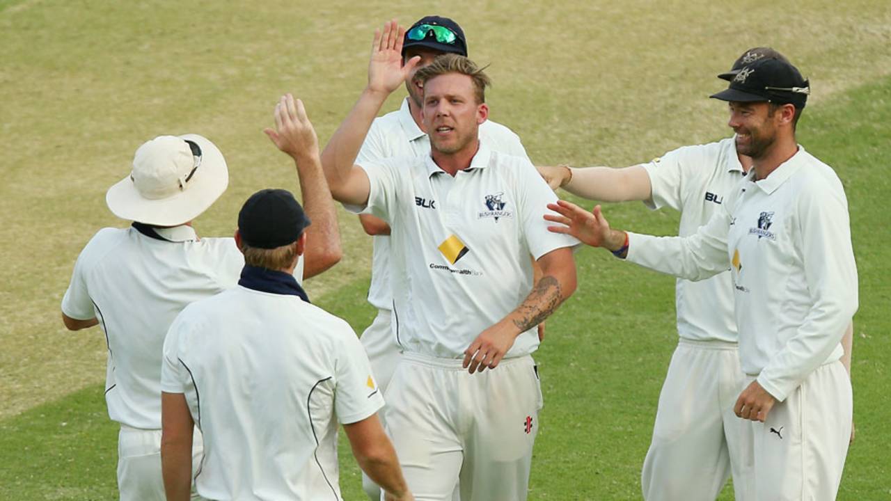 Jake Reed celebrates a wicket with his team-mates