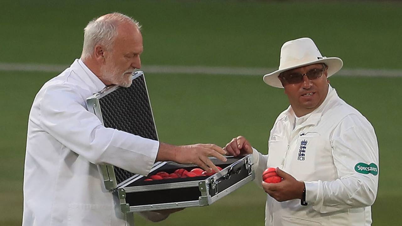 Umpire Neil Bainton selects a new pink ball from the box of replacements