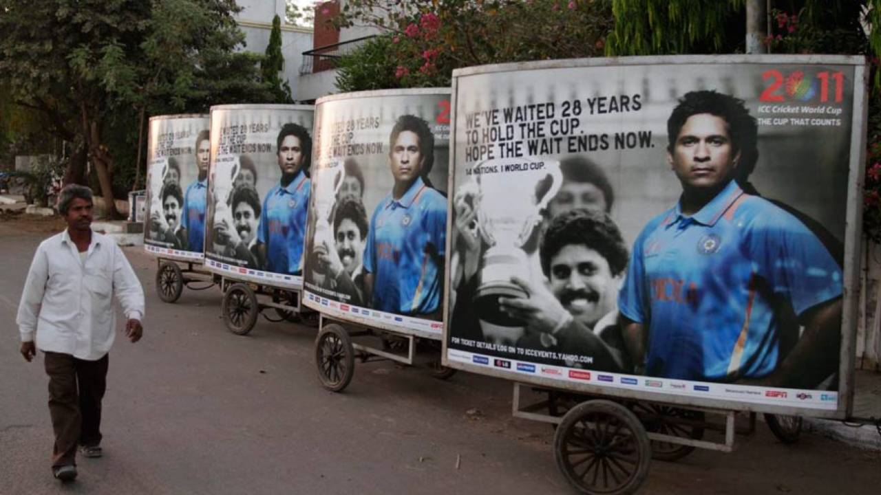 A man walks past a hoarding featuring Sachin Tendulkar and Kapil Dev in Ahmedabad, India, March 19, 2011