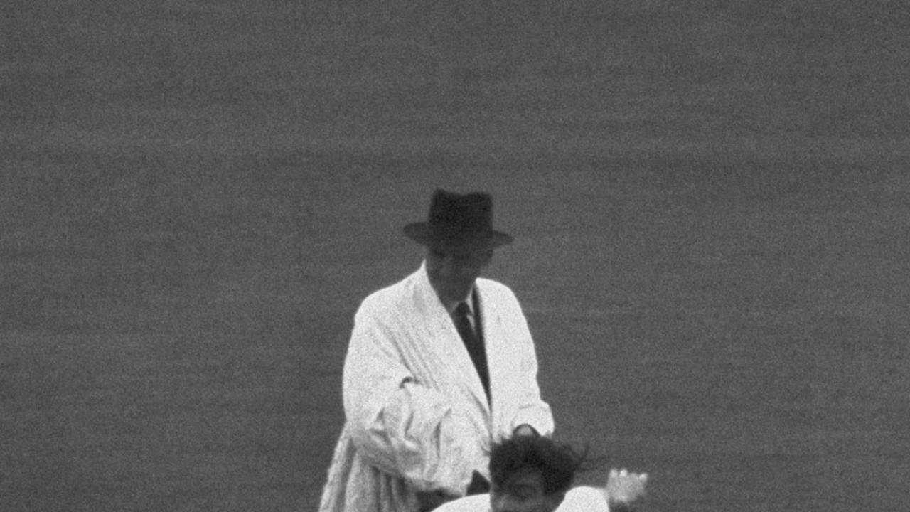 Umpire Frank Chester looks on as Fred Trueman bowls