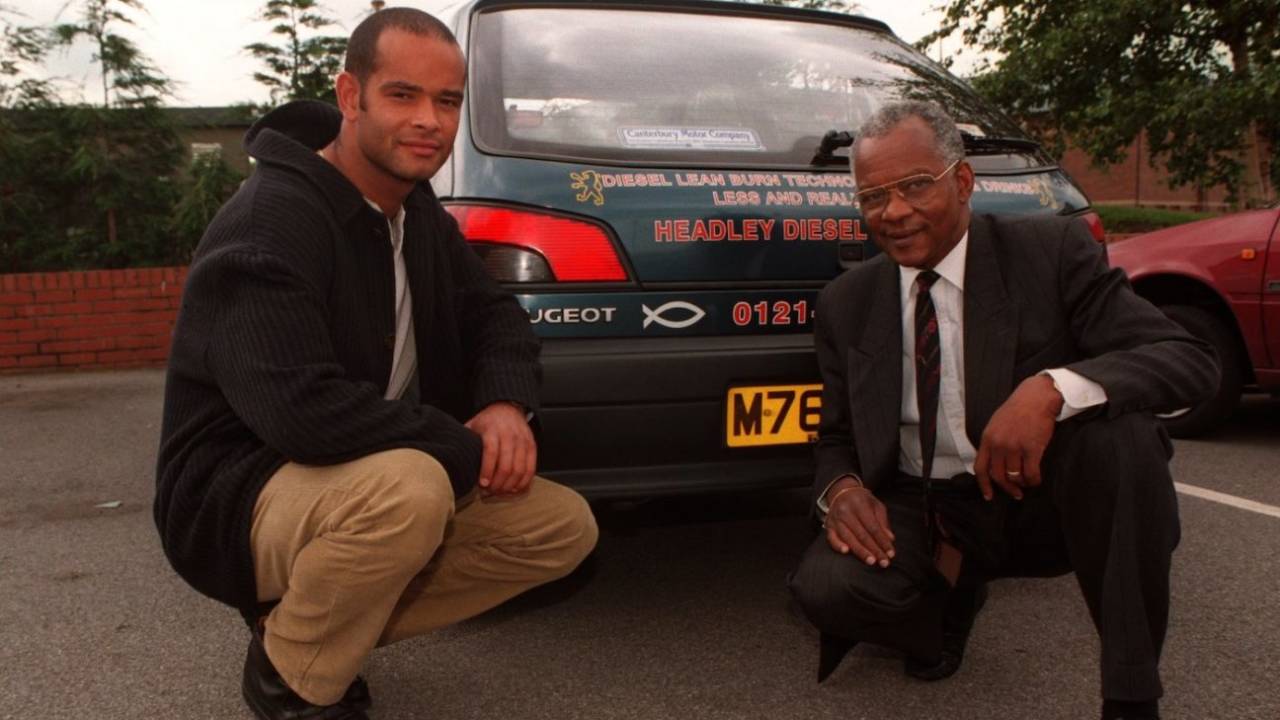 Dean and Ron Headley pose in front of an advertisement for their firm, England, July 2, 1997