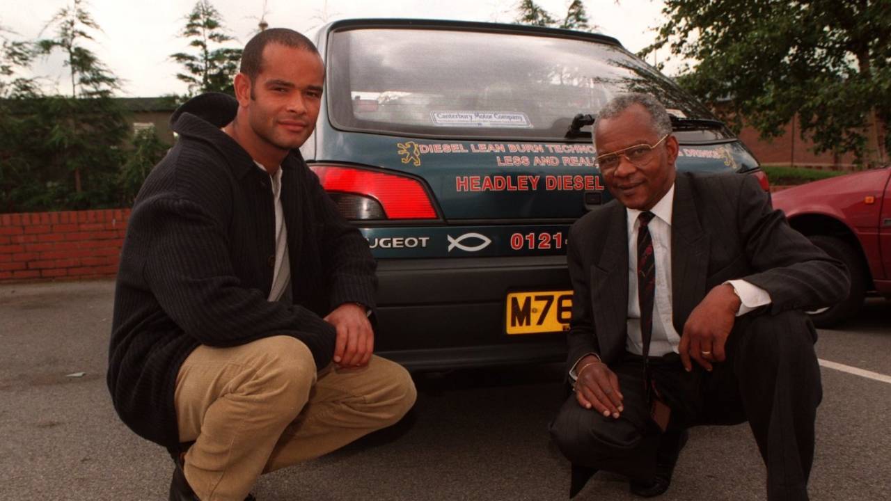 Dean and Ron Headley pose in front of an advertisement for their firm, England, July 2, 1997