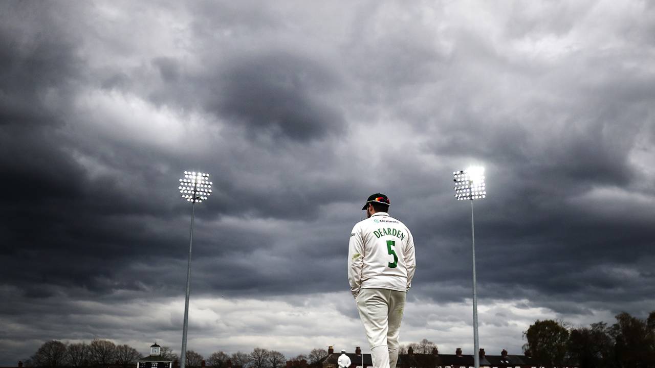 Leicestershire's Harry Dearden stands at the boundary with his hands in his pockets as dark clouds gather in the sky