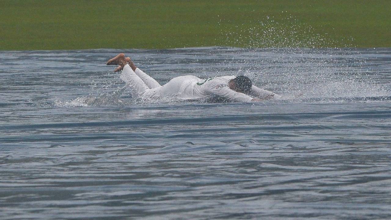 Shakib Al Hasan slides on the covers after play was called off on day two&nbsp;&nbsp;&bull;&nbsp;&nbsp;AFP/Getty Images