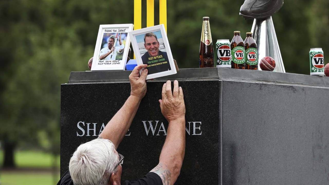 A man places a set of stumps at Shane Warne's statue at the MCG, Melbourne, March 5, 2022
