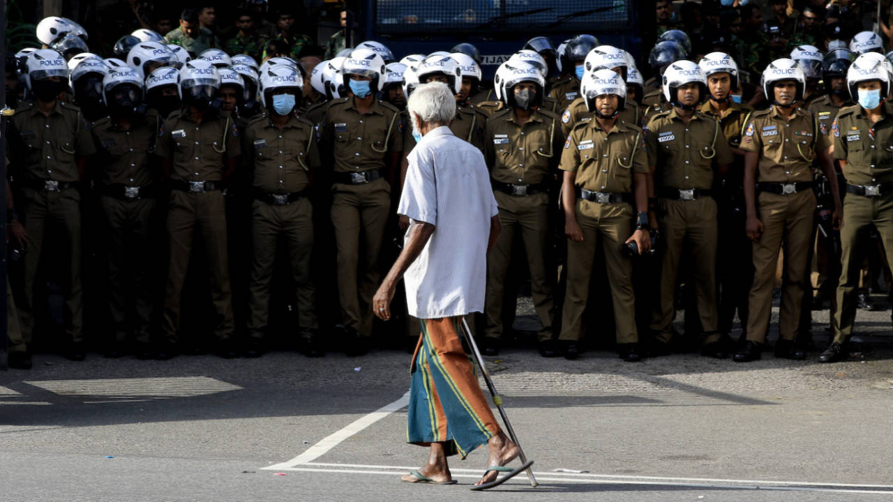 A man walks past a group of police in front of the ministry of Education during a protest, Colombo, June 10, 2022