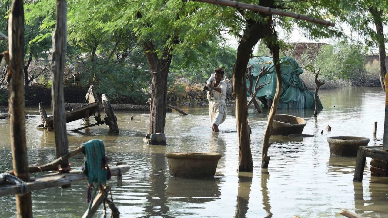 A flood-affected man wades through the waters in Shikarpur of Sindh province, August 30, 2022