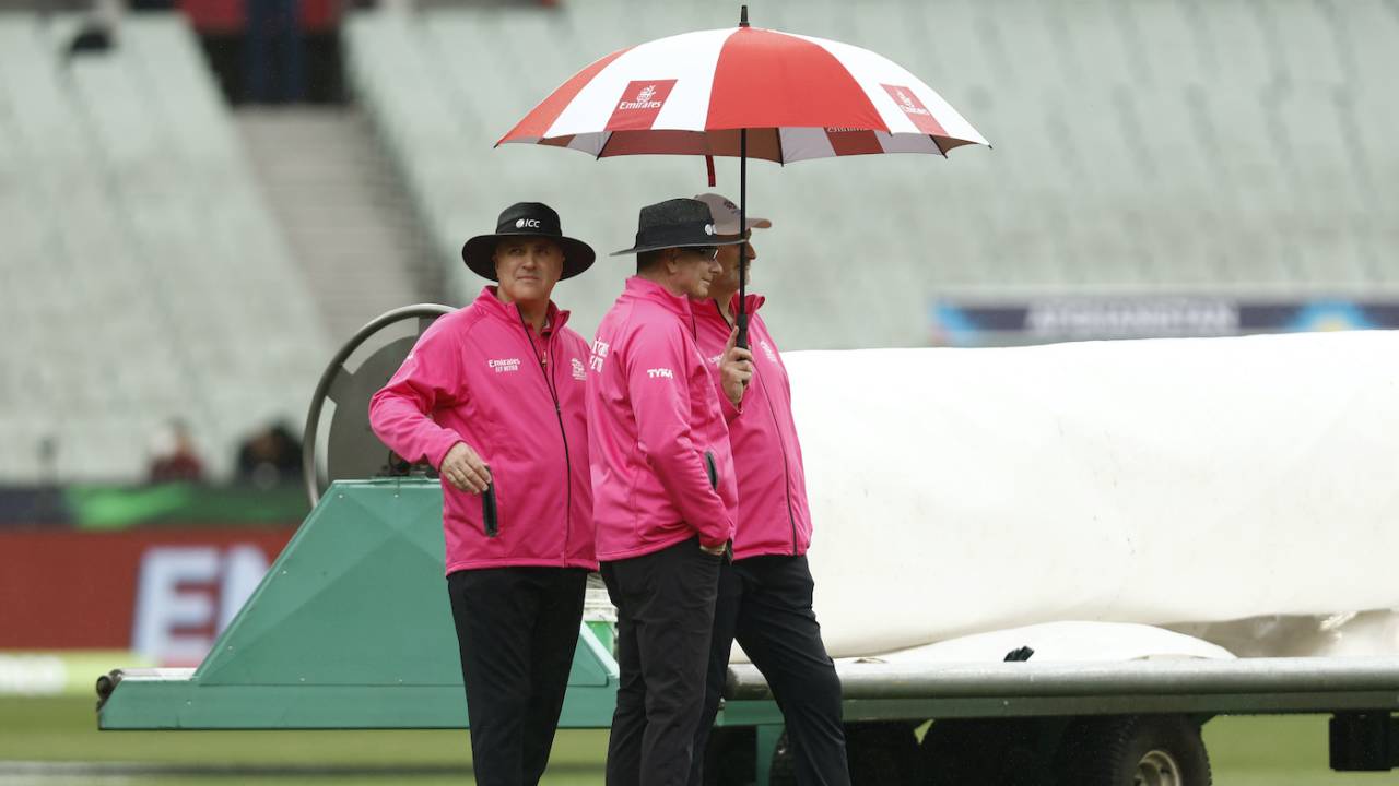 Rain has umpires Paul Reiffel and Adrian Holdstock, along with Paul Wilson, bring out the brollies