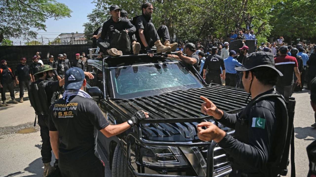 Security personnel escort a car carrying Imran Khan as he arrives at the high court in Islamabad, May 9, 2023