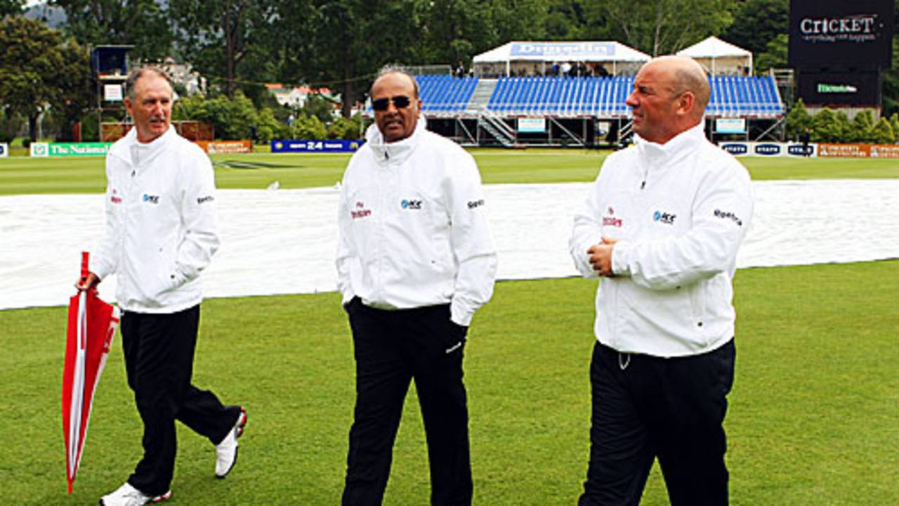 Umpires Tony Hill, Amiesh Saheba and Mark Benson inspect the wet outfield
