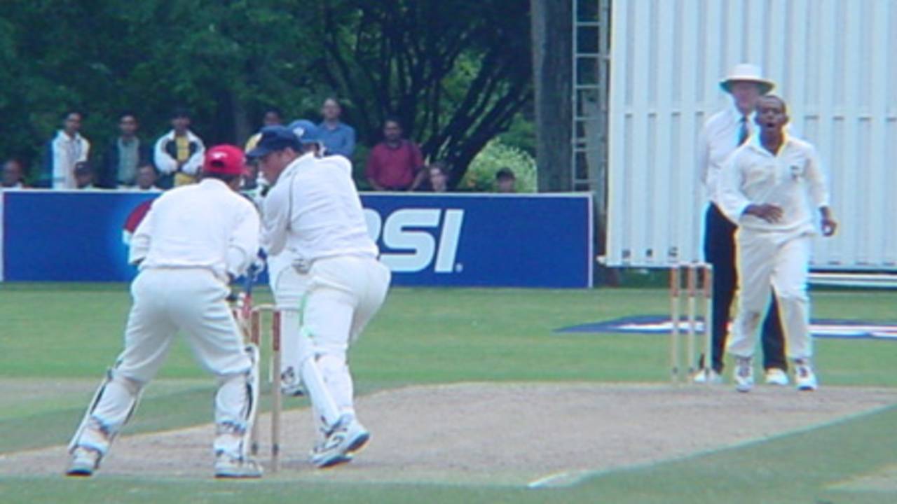 Scottish batsman Drew Parsons looks back to see he is beaten by a quicker delivery from Canadian medium pace bowler Nicholas Degroot. Wicket-keeper Ashish Bagai gloves the ball as batsman George Salmond (obscured) and Australian umpire Darrell Hair look on. ICC Trophy 2001: Canada v Scotland, Toronto Cricket, Skating and Curling Club, 17 July 2001.